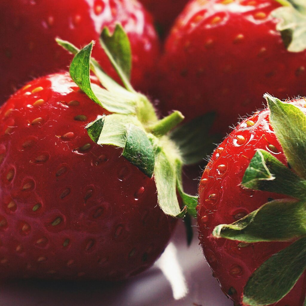 Close-up of fresh, juicy strawberries displaying vibrant red color and green leaves, perfect for healthy snack themes.